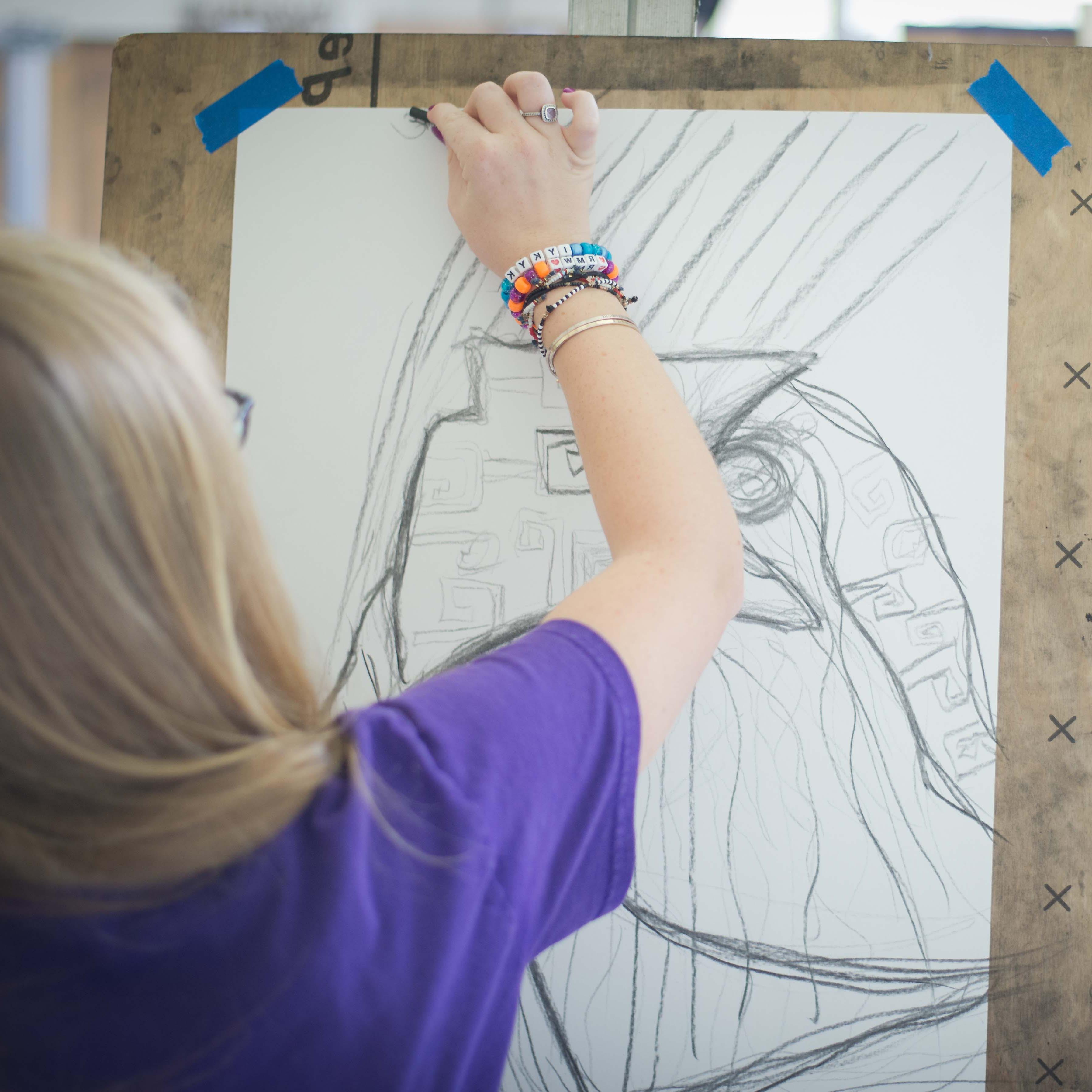 一个学生用胶带在画架上画草图